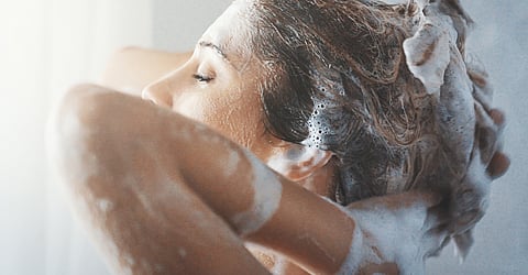 Women using shampoo to clean her hairs.