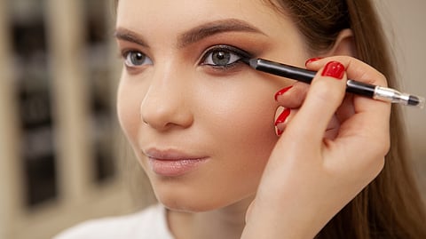 A women applying eyeliner pencil around her waterline.