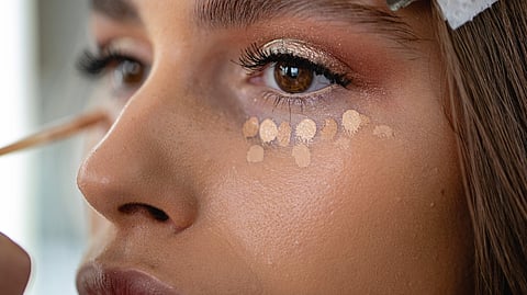 Women applying a concealer on her undereye.