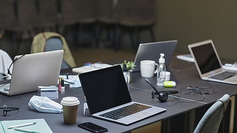 Multiple laptops set up in a conference room for business meetings.
