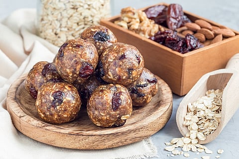 Healthy homemade energy balls with cranberries, nuts, dates and rolled oats on a wooden plate, horizontal