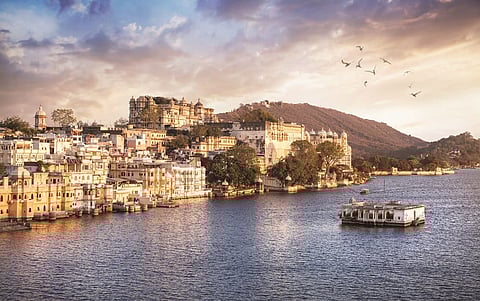 Lake Pichola with City Palace view at cloudy sunset sky in Udaipur, Rajasthan, India