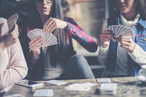 Young three best friends in cafe playing together game cards.
