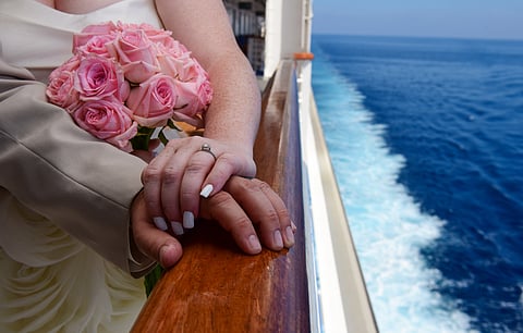 Newly married couple holding hand on a balcony of the cruise ship