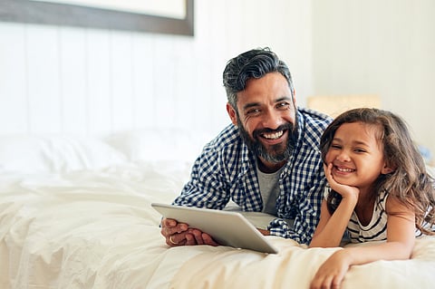 Happy, portrait and digital tablet by girl with father on a bed, relax and browsing for entertainment in their home. Face, smile and parent and with child in bedroom online for streaming or reading.