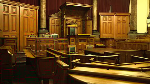 Brown wooden benches are arranged in a row, showcasing a courtroom scene.