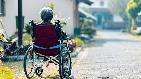Elderly person in a wheelchair outdoors, symbolizing Alzheimer's care and treatment advancements.