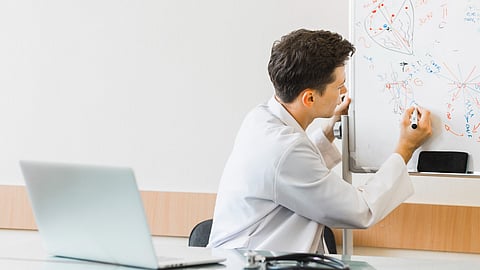 Doctor with laptop writing on whiteboard