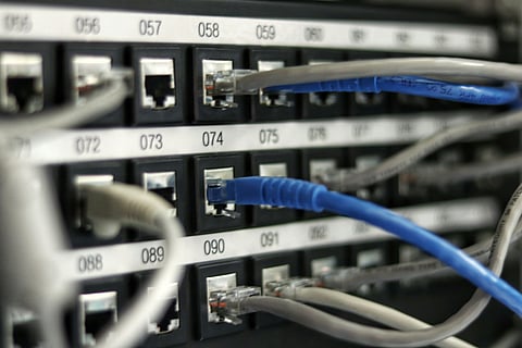 Close-up of a network switch with numerous colorful wires connected to various ports.