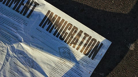 A crumbled paper is lying on the ground with the word "IMMIGRATION" written in big bold letters.