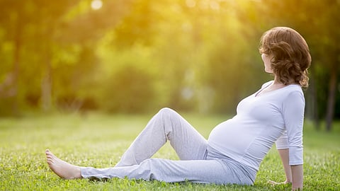 A pregnant woman in the late pregnancy stage sitting on the grass lawn