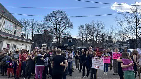 A group of people are gathered outside a "Care Clinic", holding banners of "thank you" and "reproductive rights".