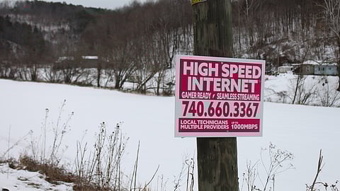A pole with a sign attached, conveying availability of high speed internet to the public.
