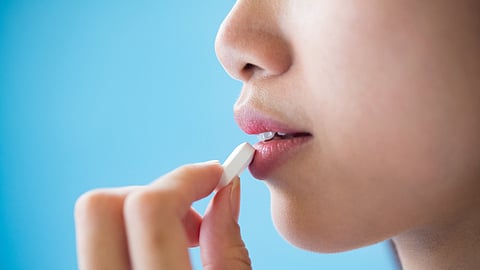 Young woman taking medicine pill after doctor order