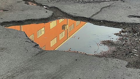 Reflection of Orange Building in Puddle on Urban Street