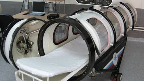 An inside of a hyperbaric oxygen therapy chamber with white bedding.