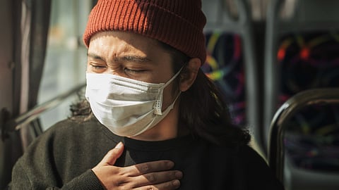 Sick woman in a mask having a difficulty in breathing.