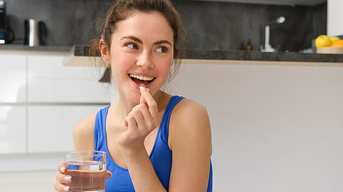Close-up portrait of a woman taking vitamins, and a glass of water
