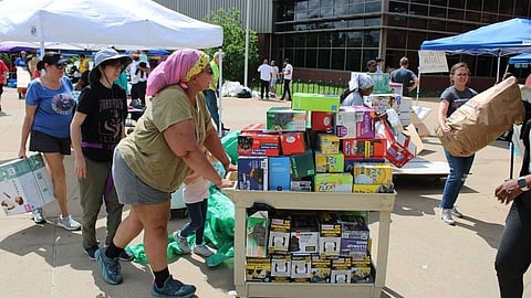 A group of people are helping each other by moving boxes and supplies.