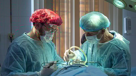 Two surgeons in surgical attire focused on an operation in a hospital operating room.
