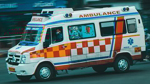 An ambulance vehicle is rushing on the road with flashing lights.