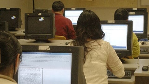A number of candidates taking an online exam in a room full of computers.