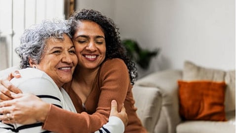 An elderly and a young women hugging each other with smiles.
