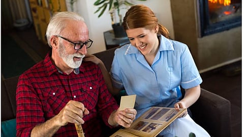 An elderly man looking at a photo with a nurse.