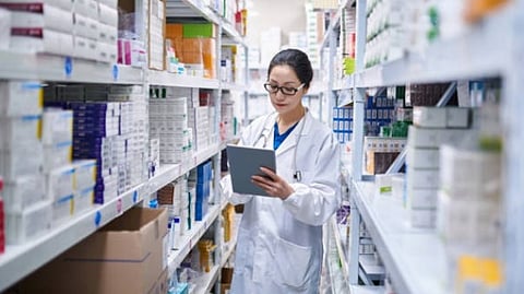 A woman healthcare professional wearing a white lab coat noting down something in a pharmacy.