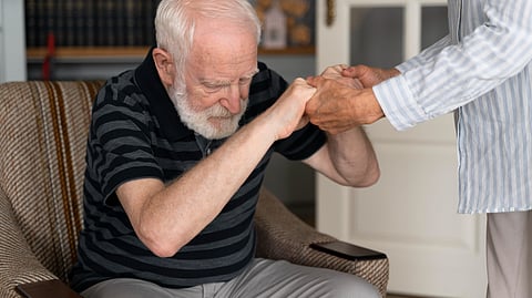 An old man being helped to get up from the chair.
