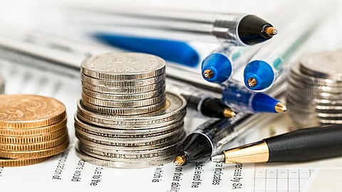 An image showing some coins and pen with documents