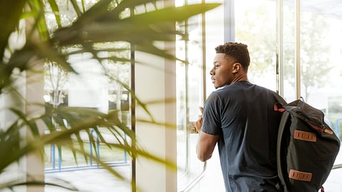 A man is opening a glass door to go outside a building.