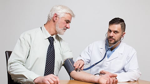 An elderly man is getting his blood pressure checked by a doctor. 
