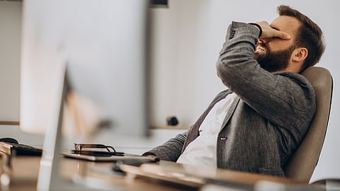 A businessman looking tired at his desk during working hours.
