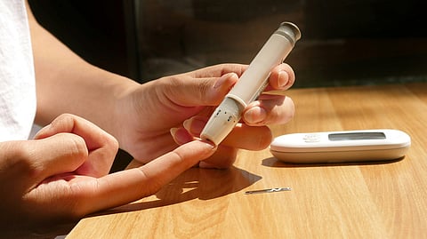 The picture shows a woman checking blood sugar levels using a glucometer.