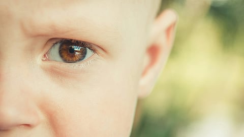 Close-up of a child’s eye, symbolizing early vulnerability and premature aging.