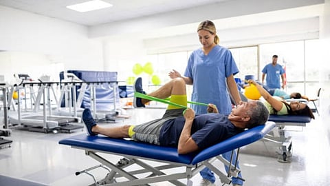 A patient lying down in a stretcher and doing some movements with the help of some elastics.