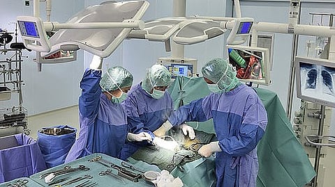 Doctors in operating room wearing full operating gear performing surgery