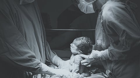 A newborn being taken out during a caesarian operation from mother's womb in an operation theatre.