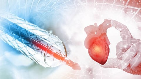 A syringe with catheter is positioned next to a heart held by a hand, symbolizing heart health.