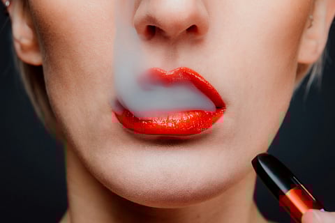 person with red lipstick, vapes and They are taking a puff from a vape.