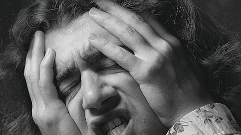 An representative image of a person holding his head in distress, visibly overwhelmed by panic attacks.