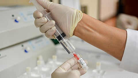 Image showing a scientist collecting some transparent liquid into a vial.