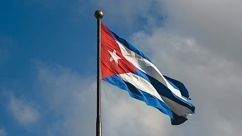 The Cuban flag billows in the wind, showcasing its red, white, and blue colors and distinctive star emblem.