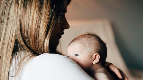 A woman on maternity leave gently cradles a baby in her arms.