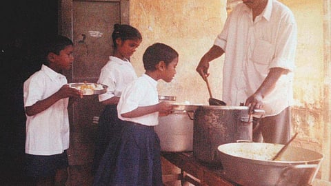 Visuals of the mid-day meal in school, where a man is serving food to children.