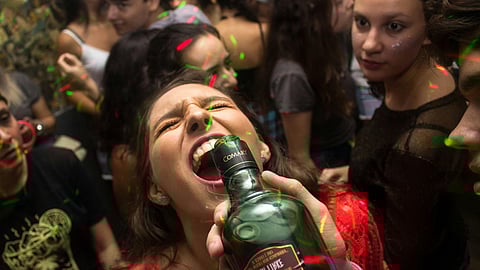 Young adults in a crowd drinking alcohol at a party.