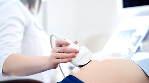 A doctor is seen performing an ultrasound on a pregnant woman.