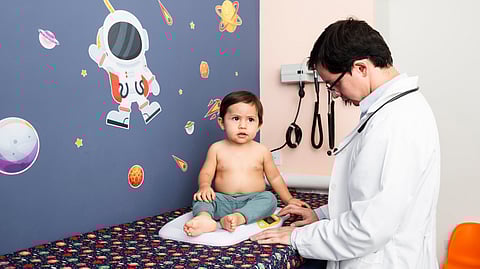 A doctor is checking a toddler on the examination table.