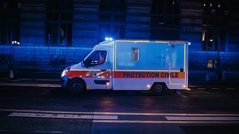 A white and blue ambulance parked on a street at night. 